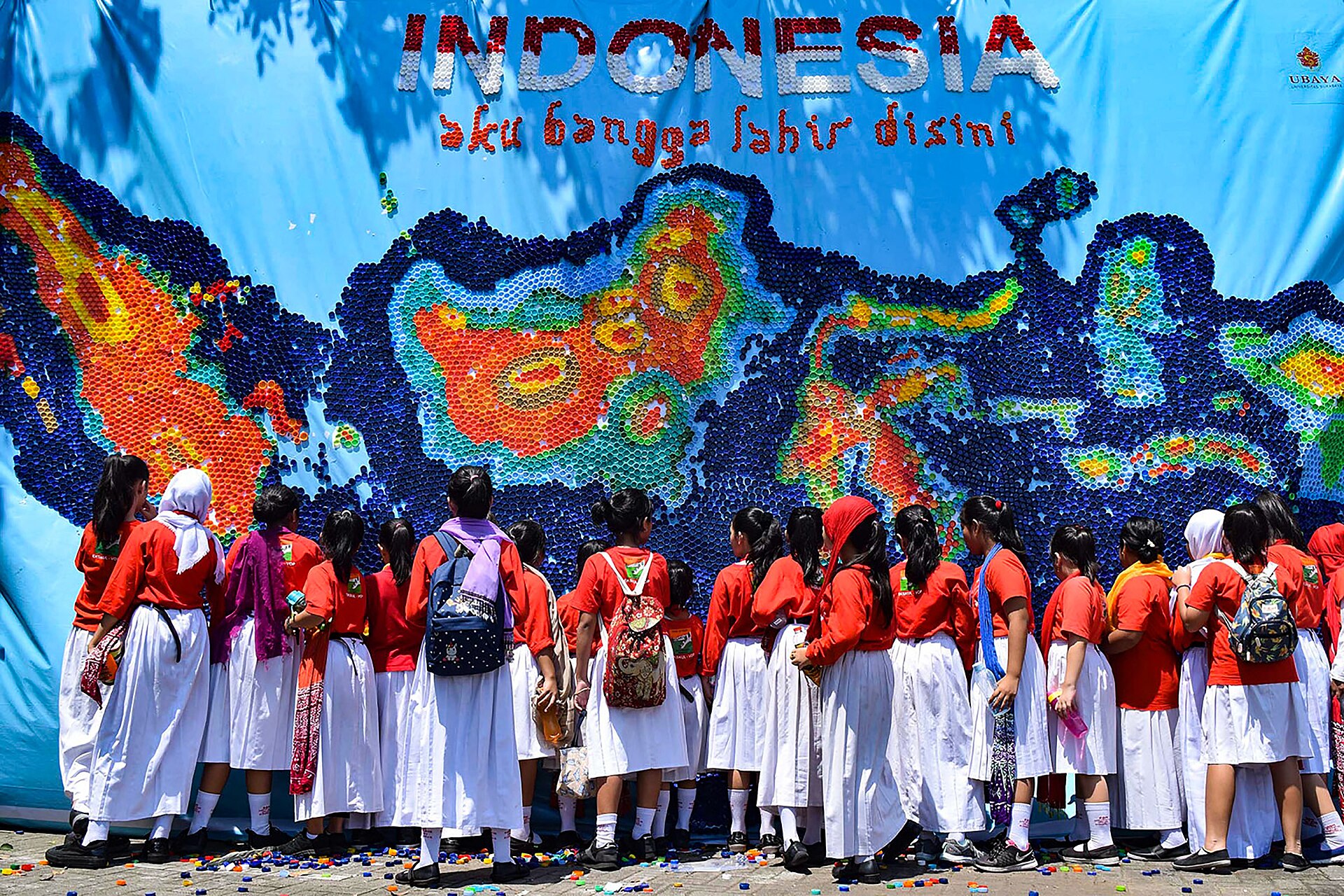 Rombongan pelajar berdiri di depan mozaik besar dari tutup botol bekas